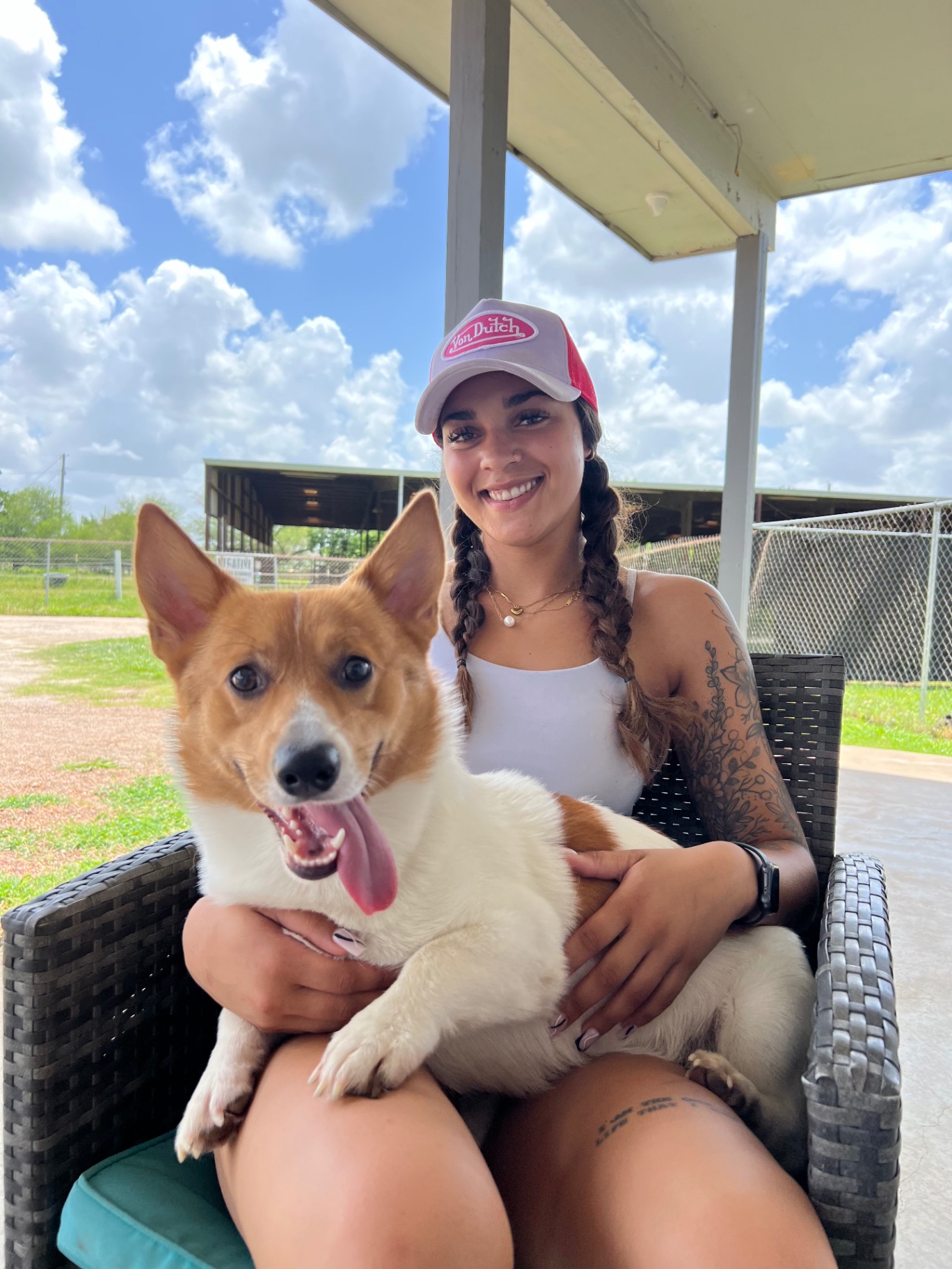 Trainer holding a happy Corgi outdoors at the training facility